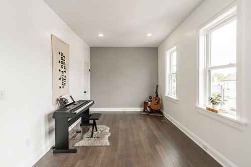 Bonus room with a digital piano, acoustic guitar and a light gray accent wall