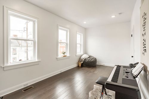 Bright bonus room with three windows, a beanbag chair and hardwood floors