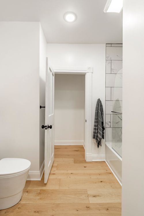Bathroom nook with an open closet door and a striped towel near a marble tile shower