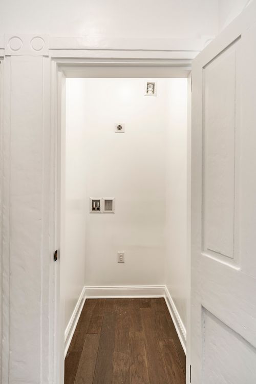 Empty laundry nook with rough-in hookups and wood flooring