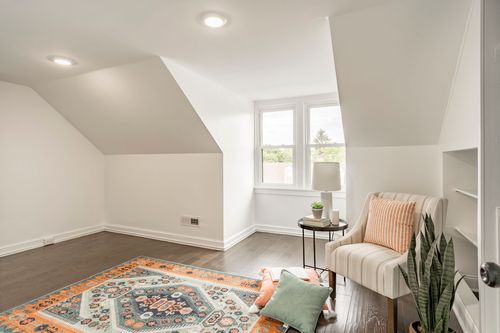 Sunny attic bonus room with a striped armchair, patterned rug and built-in shelving