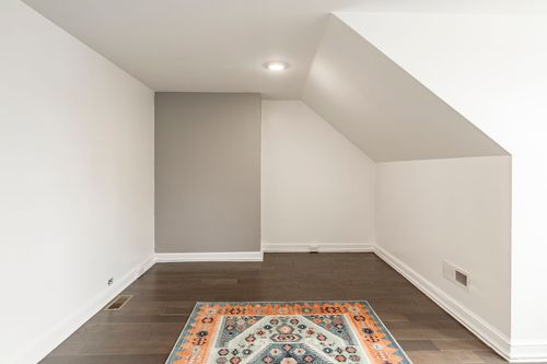 Empty attic bonus room corner with a gray accent wall and a patterned area rug