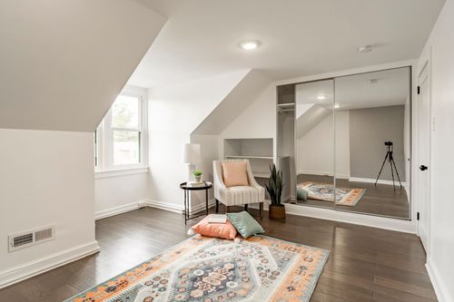Attic bedroom with sloped ceiling, mirrored closet and a Southwestern-style area rug