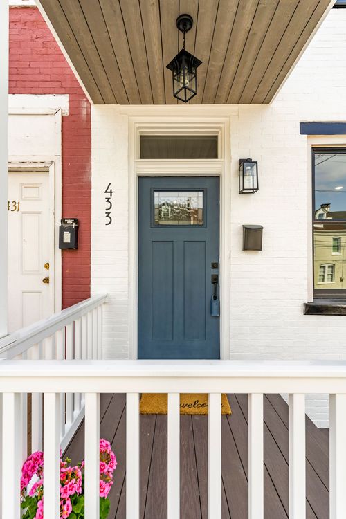 Covered porch with pendant light, slate-blue door and a welcome mat on wood decking