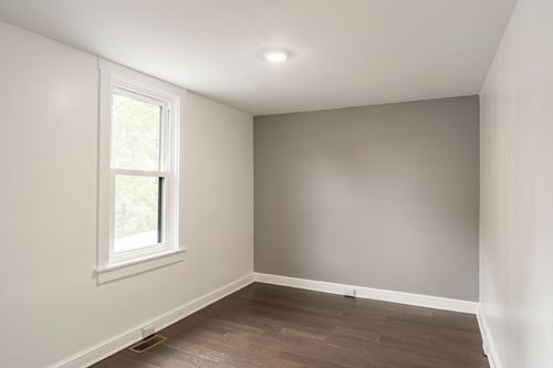 Empty bedroom with a light gray accent wall and a single window