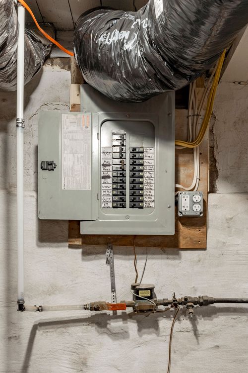 Close-up of an electrical breaker panel mounted on a basement wall