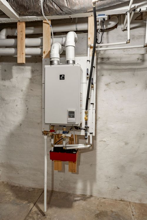 Close-up of a wall-mounted tankless water heater with copper piping