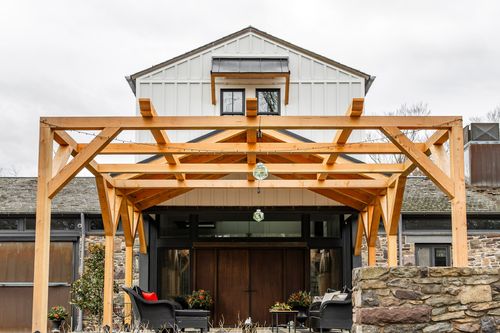 Front view of a timber pavilion framing a gabled dormer above dark wood double doors