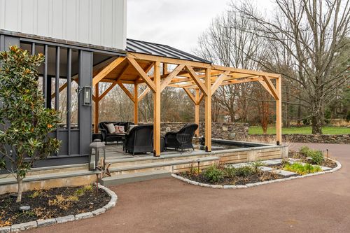Wicker outdoor seating beneath a cedar timber-frame pergola on a bluestone patio