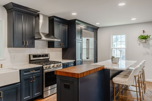 Brass cabinet pulls on navy blue drawers beneath a white quartz countertop
