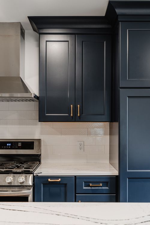 Built-in microwave drawer beneath a white quartz counter in a navy kitchen island