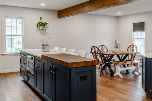 Navy cabinets and stainless range beneath a reclaimed wood ceiling beam