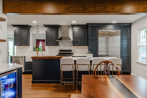 Navy kitchen with a reclaimed wood ceiling beam, farmhouse touches and a built-in wine fridge