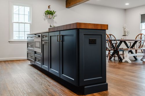 Close-up of navy cabinetry with brass hardware beside a stainless range