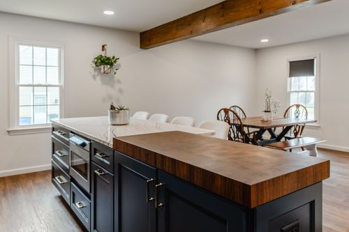 Navy kitchen with white quartz waterfall island and hallway view beyond