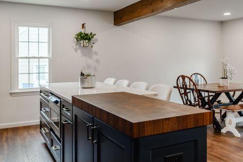 Brass faucet and gas range in a navy kitchen with white subway tile backsplash