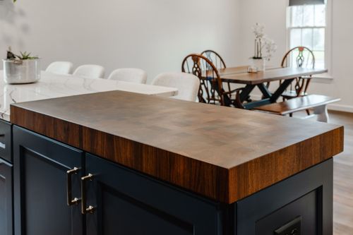 Navy cabinets with brass pulls beside a farmhouse sink and pendant light