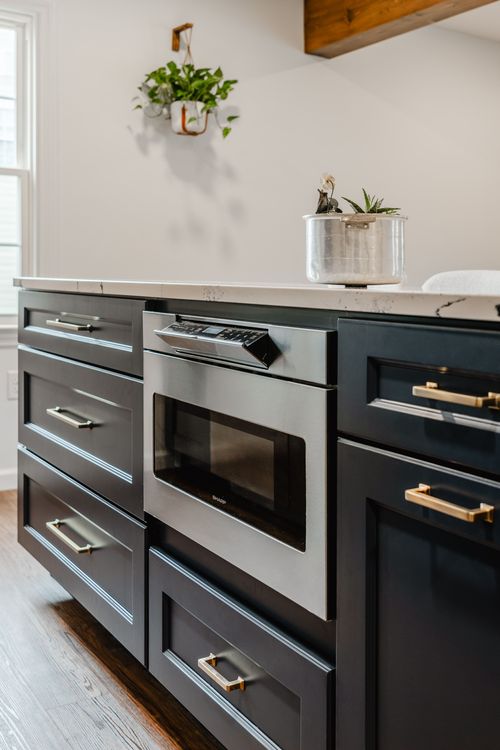 Stainless gas range and hood centered beneath crown-molded navy cabinets