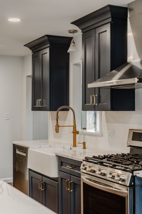 Navy cabinets and stainless range hood with subway tile backsplash