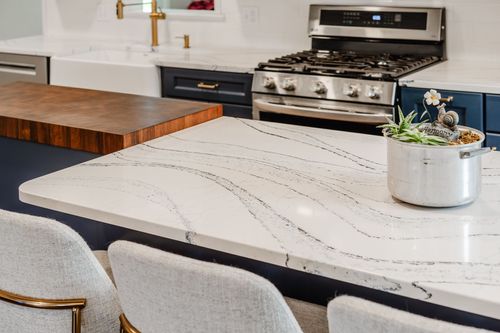 Close-up of a white quartz waterfall island counter with a potted succulent