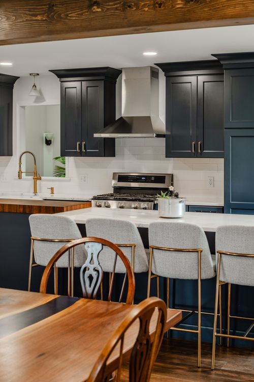 Navy kitchen island seating with stainless hood, range and dining table beyond
