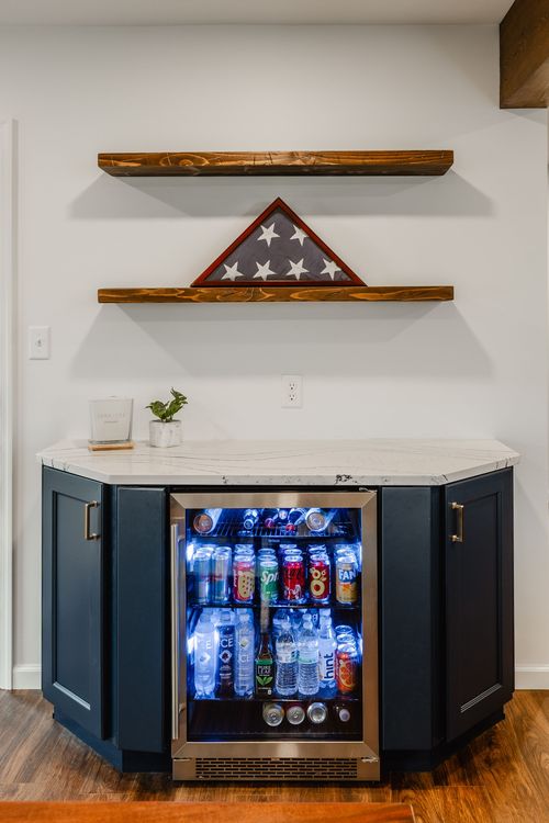 Navy corner beverage bar with a folded flag display on floating wood shelves
