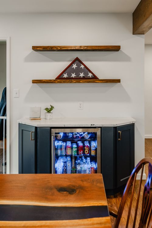 Beverage bar with glass-front fridge and flag shadow box, dining table in foreground