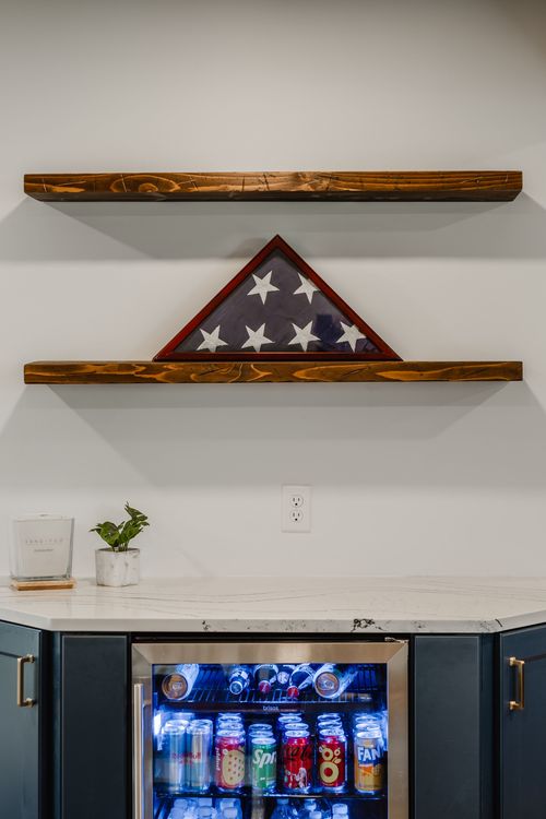 Close-up of a folded flag shadow box mounted between rustic floating wood shelves