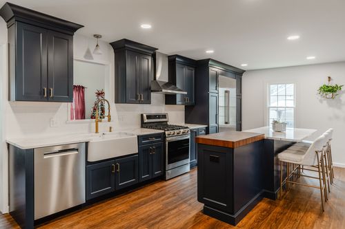 Navy blue kitchen with brass hardware, subway tile backsplash and a farmhouse sink
