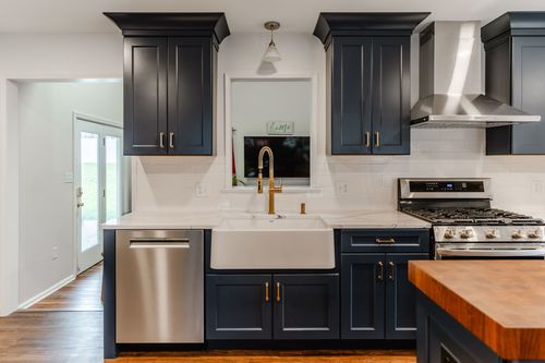 Close-up of a stainless range hood flanked by navy shaker cabinets
