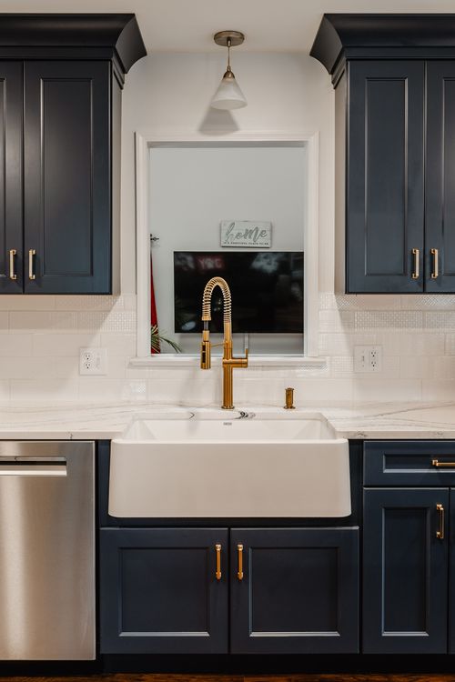 Stainless gas range and hood centered between navy cabinets and white subway tile