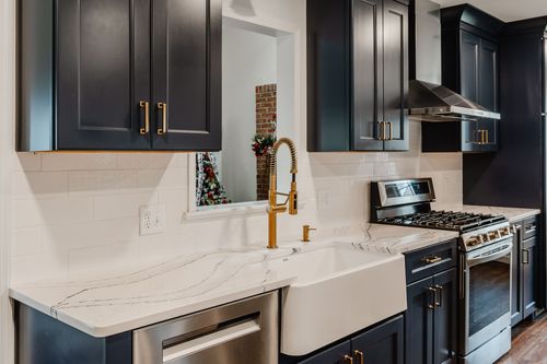 Close-up of a white quartz waterfall countertop meeting navy cabinetry with a brass pull
