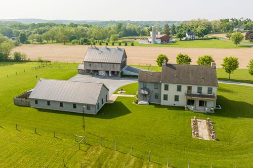 Aerial view of a farmhouse, outbuilding and barn with a distant grain silo