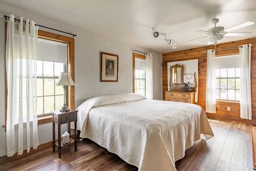 Bedroom with wood-paneled wainscoting, ceiling fan and crisp white bedding