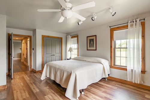 Bedroom with light wood floors, gray closet doors and a view down the hallway