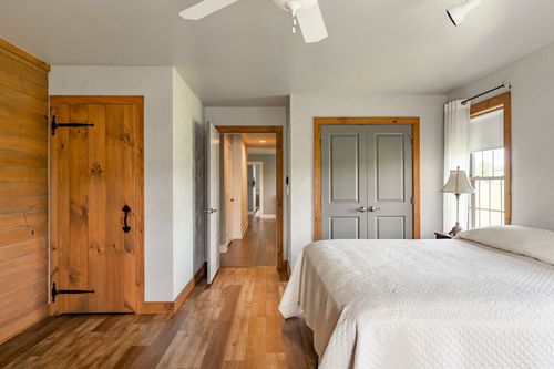 Bedroom featuring a rustic wood plank door, gray built-ins and hallway views beyond