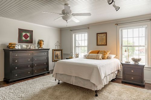 Bedroom with beadboard ceiling, dark wood dresser and a plush area rug