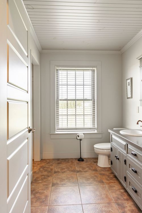 Bathroom with beadboard ceiling, gray vanity and warm tile flooring