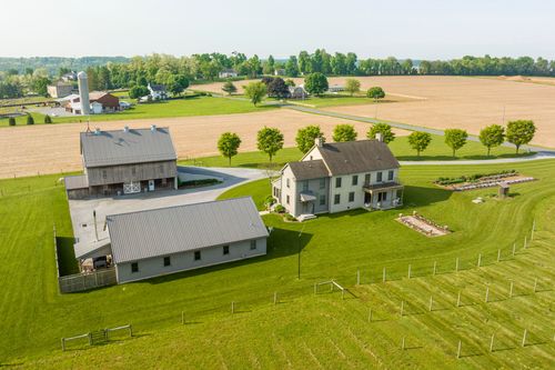 Aerial view of a farmhouse and barn courtyard beside a detached garage