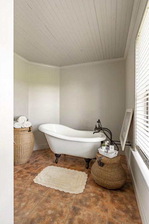Bathroom with a white clawfoot tub, wicker baskets and patterned tile floor