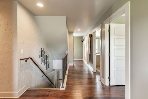 Upstairs landing with a gallery wall, wood railing and rich hardwood floors
