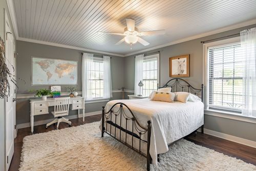 Bedroom with a wrought iron bed, white writing desk and a shag area rug