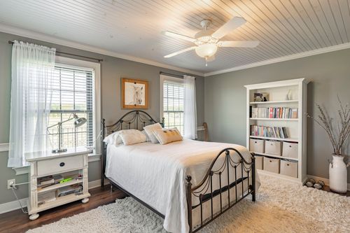 Bedroom with a wrought iron bed, white storage bookshelf and gray walls