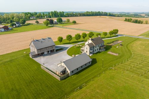 Aerial view of a farmhouse and barn surrounded by rolling farm fields