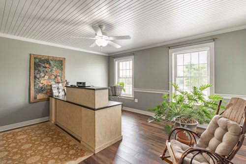 Sitting room with a built-in reception desk, wicker chairs and floral tapestry art