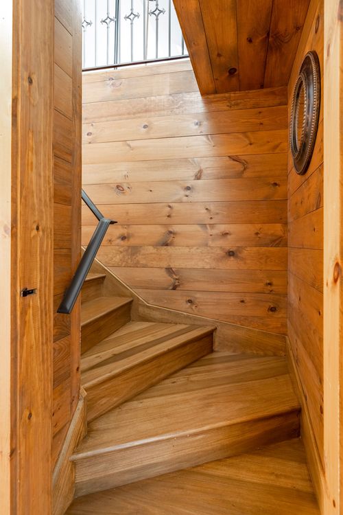 Knotty pine staircase winding up between wood-paneled walls