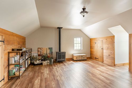 Vaulted loft room with a freestanding wood stove and knotty pine accent wall
