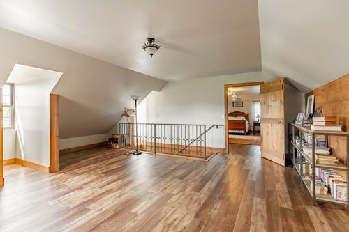 Open loft landing with wood floors, metal railing and bedroom views beyond