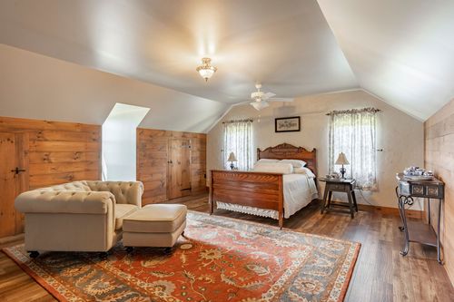 Vaulted bedroom with a tufted chaise lounge, wood-paneled walls and an oriental rug