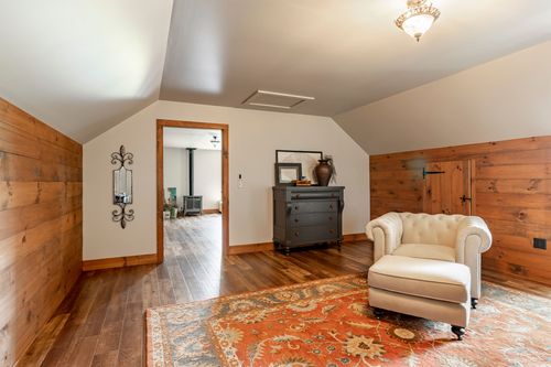 Sitting area with a tufted armchair, dark dresser and an oriental rug